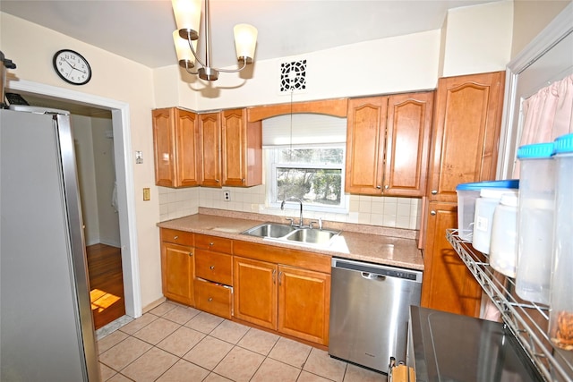 kitchen featuring stainless steel appliances, brown cabinetry, a sink, and tasteful backsplash