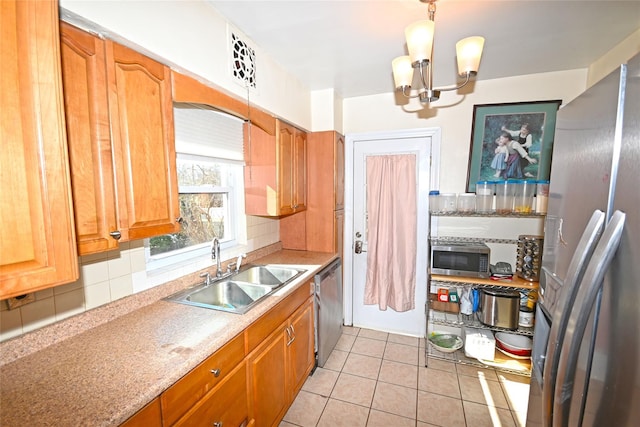 kitchen with light tile patterned floors, appliances with stainless steel finishes, a sink, light countertops, and backsplash