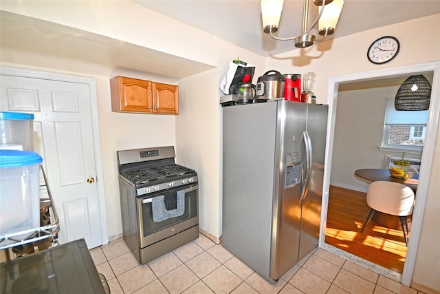 kitchen featuring light tile patterned floors, stainless steel appliances, brown cabinetry, and a chandelier