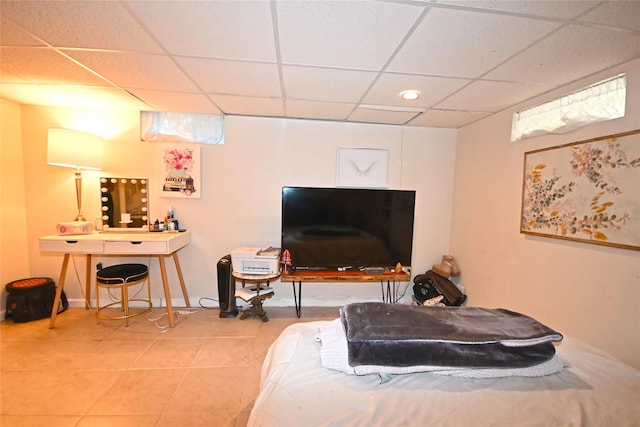 bedroom featuring tile patterned flooring, a drop ceiling, and baseboards