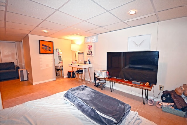 tiled bedroom with a paneled ceiling and baseboards