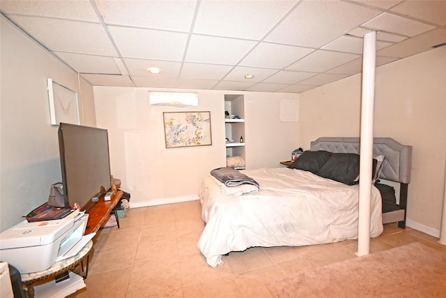 bedroom with a paneled ceiling, tile patterned flooring, and baseboards