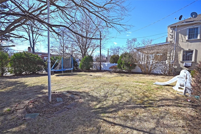 view of yard with a trampoline and fence