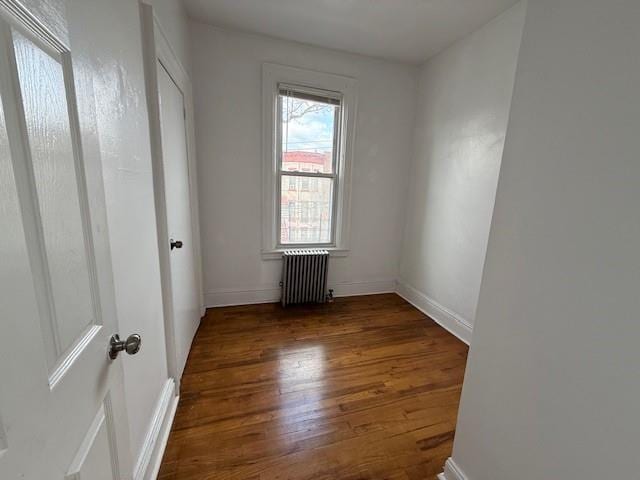 unfurnished bedroom with radiator heating unit, baseboards, and dark wood finished floors