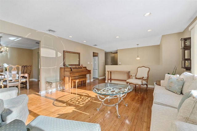 living room with a notable chandelier, recessed lighting, visible vents, light wood-type flooring, and baseboards