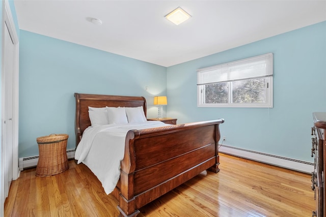 bedroom with light wood finished floors and a baseboard heating unit