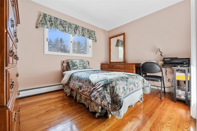 bedroom featuring a baseboard heating unit and light wood-style flooring