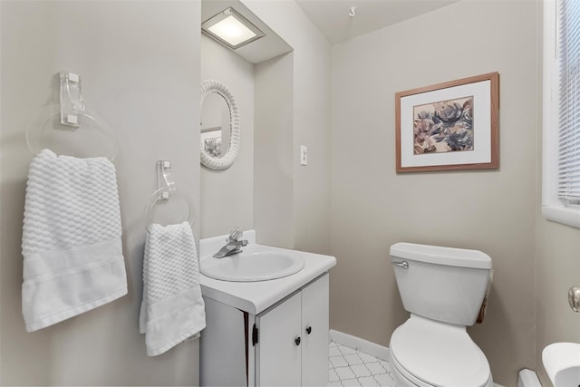 half bathroom featuring baseboards, vanity, and toilet