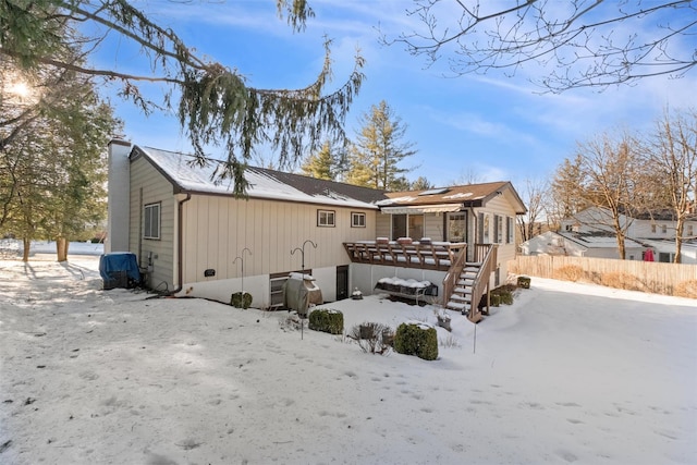 snow covered rear of property with a chimney, stairway, and fence