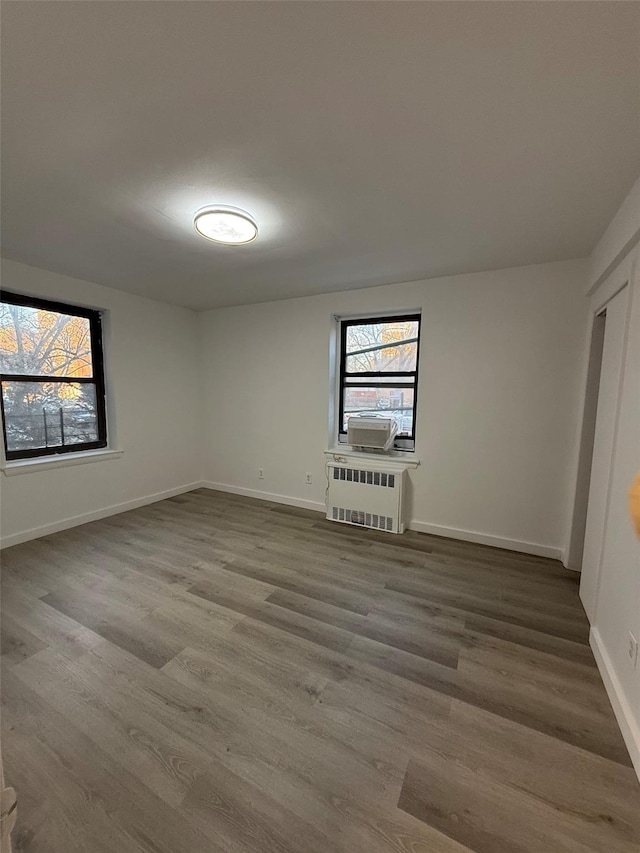 unfurnished bedroom with radiator heating unit, baseboards, and wood finished floors