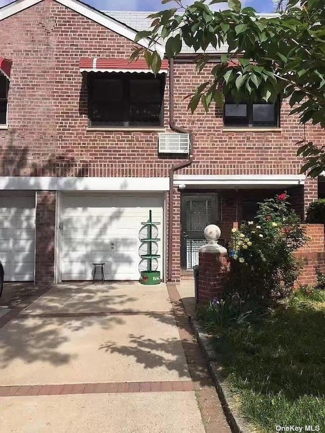 view of front of house featuring driveway, brick siding, and a wall mounted AC