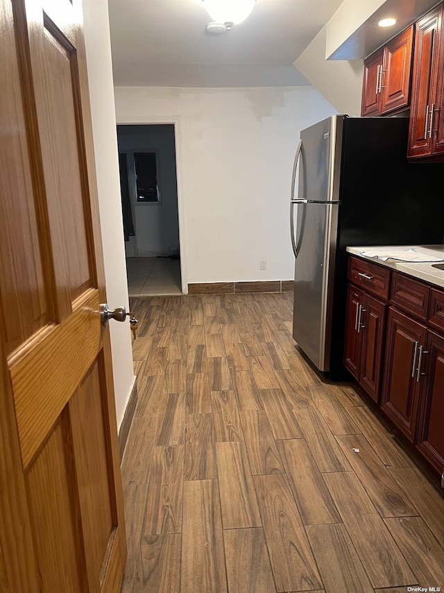 kitchen with wood finished floors, baseboards, light countertops, dark brown cabinets, and freestanding refrigerator