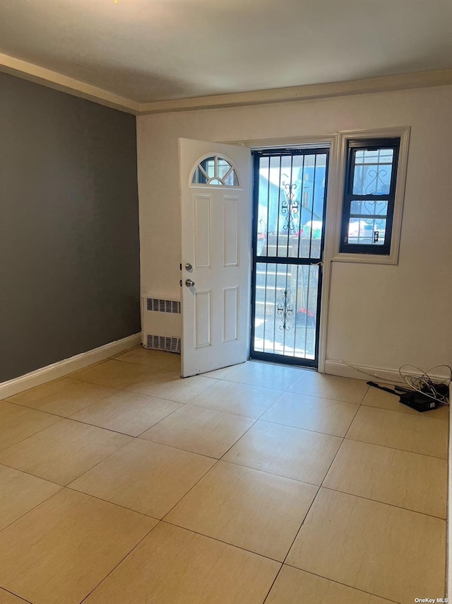 foyer with radiator, light tile patterned floors, and baseboards