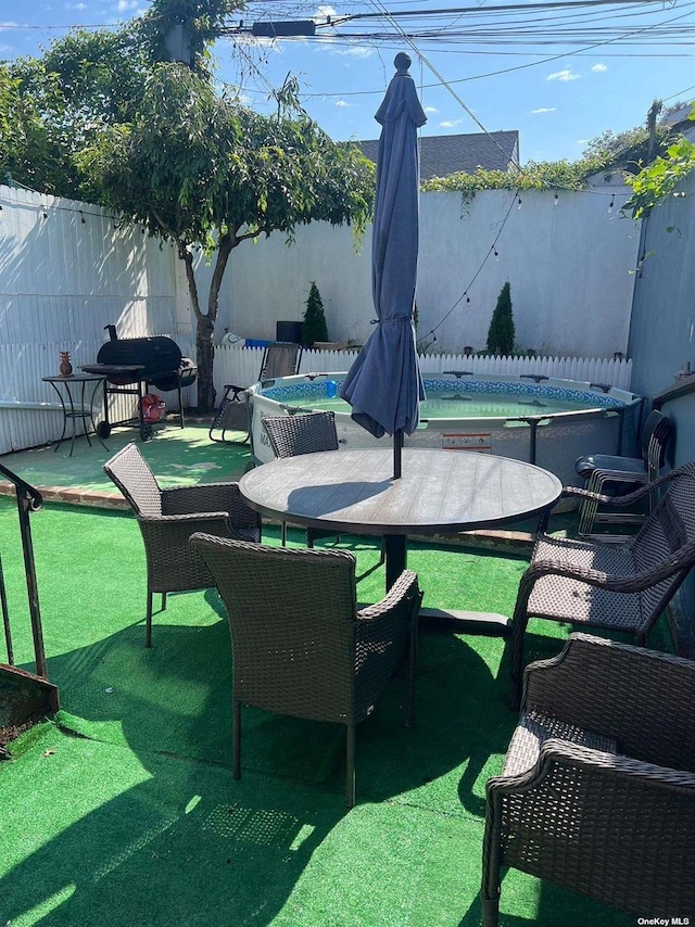 view of patio / terrace with outdoor dining space, a fenced backyard, and a hot tub