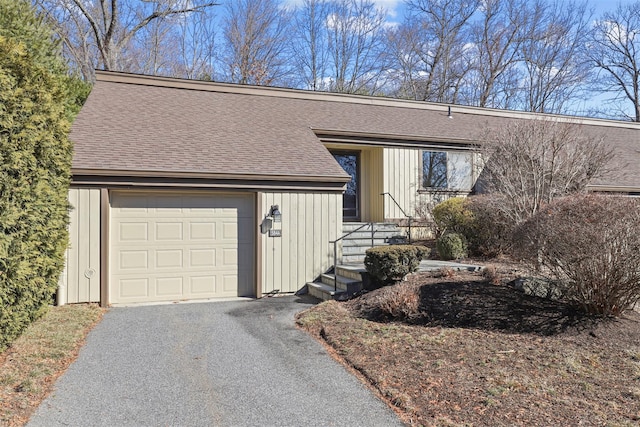 view of front of property featuring driveway and roof with shingles