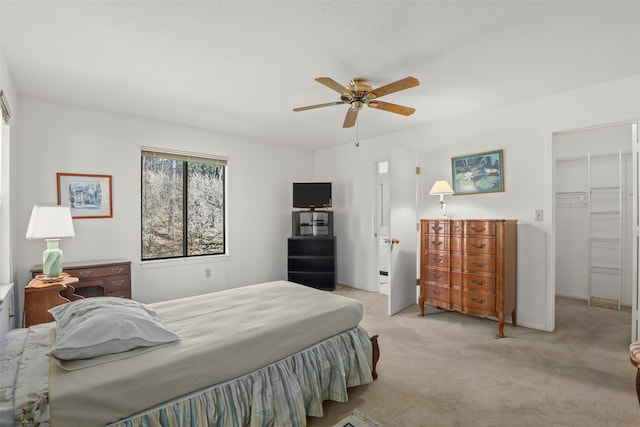 bedroom with a ceiling fan, a walk in closet, a closet, and light colored carpet