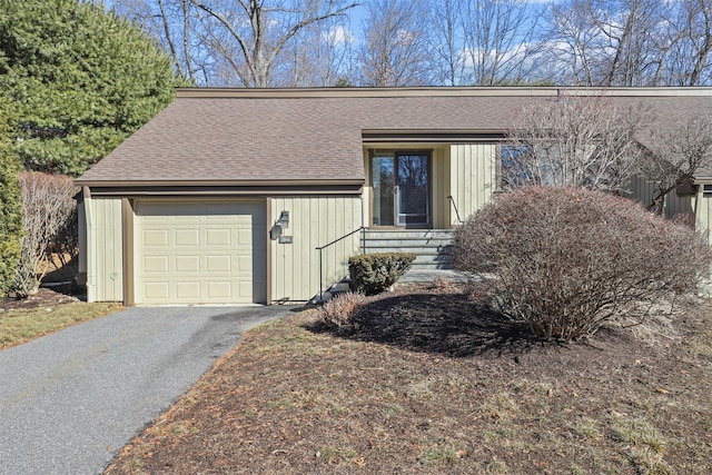 view of front of house featuring driveway, an attached garage, and roof with shingles