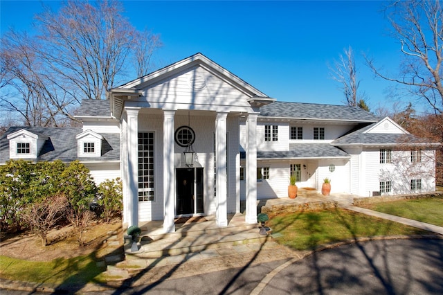 neoclassical home featuring a shingled roof and a porch