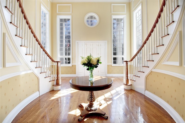 entrance foyer featuring baseboards, stairway, wood finished floors, and wallpapered walls