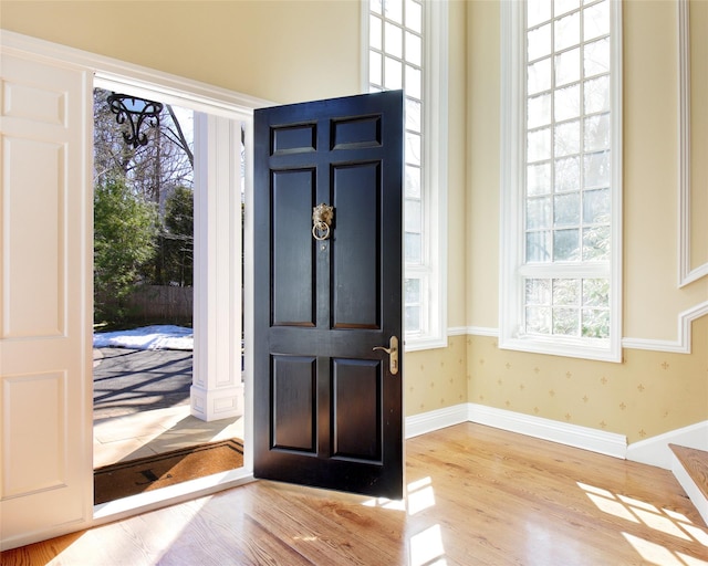 entryway with baseboards, a healthy amount of sunlight, wallpapered walls, and wood finished floors