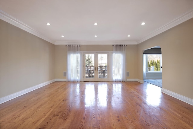 spare room featuring ornamental molding, arched walkways, and baseboards