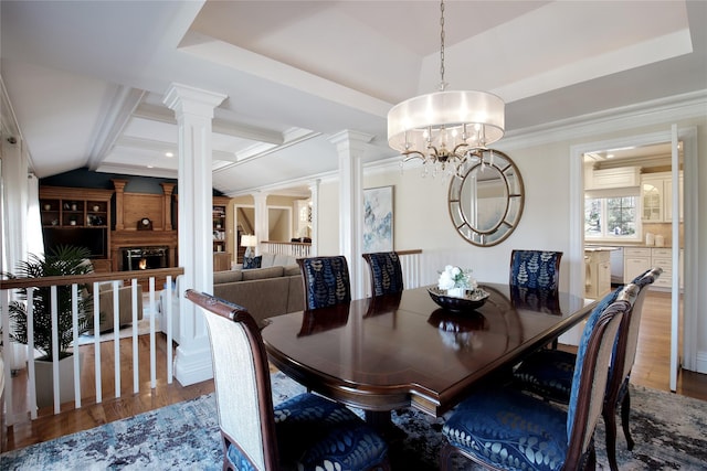 dining area featuring lofted ceiling, a tray ceiling, ornate columns, and wood finished floors