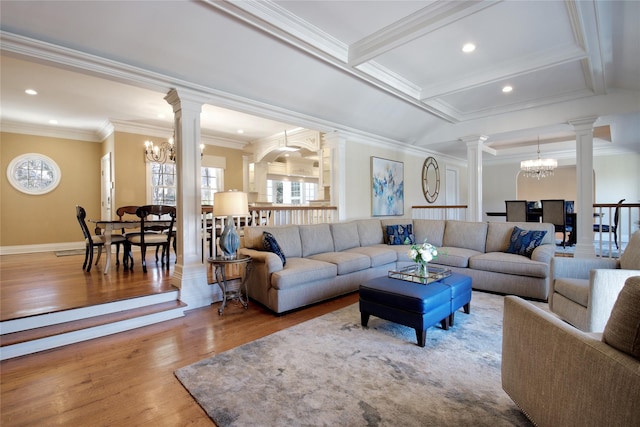 living room featuring ornamental molding, a notable chandelier, decorative columns, and wood finished floors