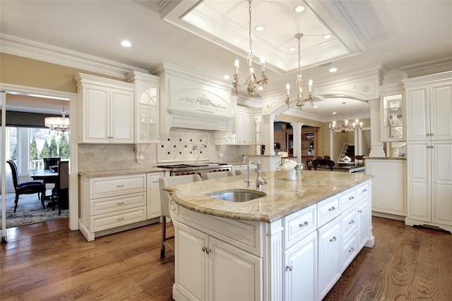 kitchen featuring arched walkways, a chandelier, dark wood-style flooring, a sink, and ornate columns