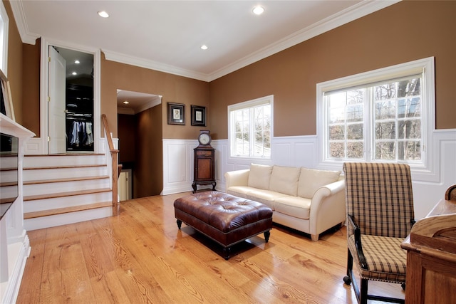 living room with radiator, wainscoting, light wood finished floors, and stairs