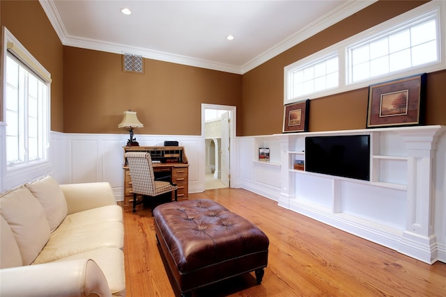 living area featuring wainscoting, crown molding, visible vents, and wood finished floors