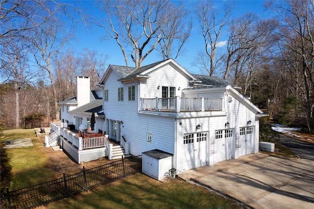 exterior space featuring a yard, a chimney, concrete driveway, fence, and a garage