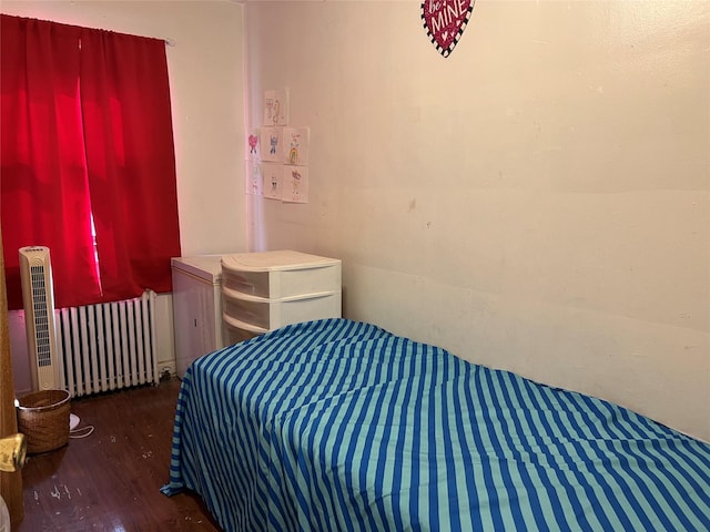 bedroom featuring radiator heating unit and dark wood-type flooring