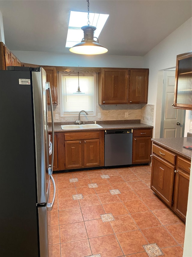 kitchen with appliances with stainless steel finishes, a sink, and brown cabinets