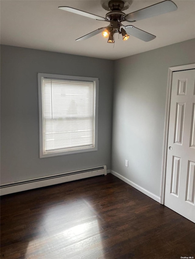 empty room featuring a ceiling fan, a baseboard radiator, dark wood finished floors, and baseboards