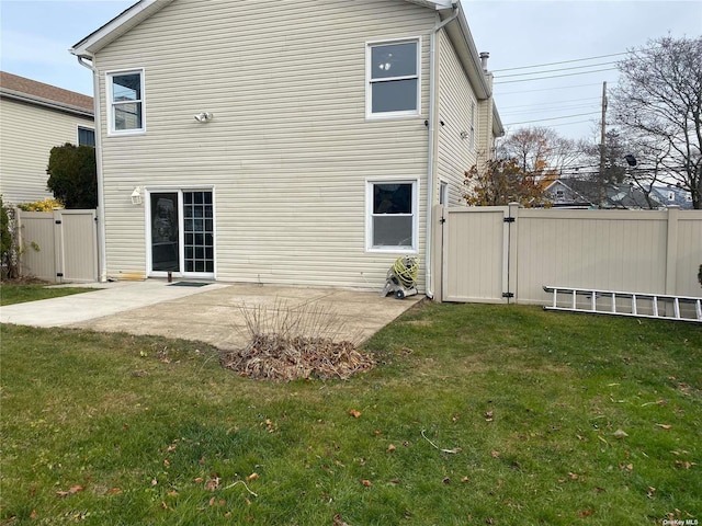 back of property featuring a gate, a patio, a lawn, and fence