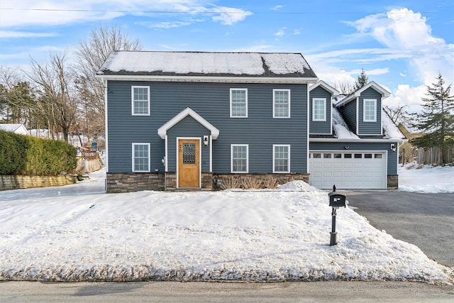 colonial house with aphalt driveway, stone siding, and a garage