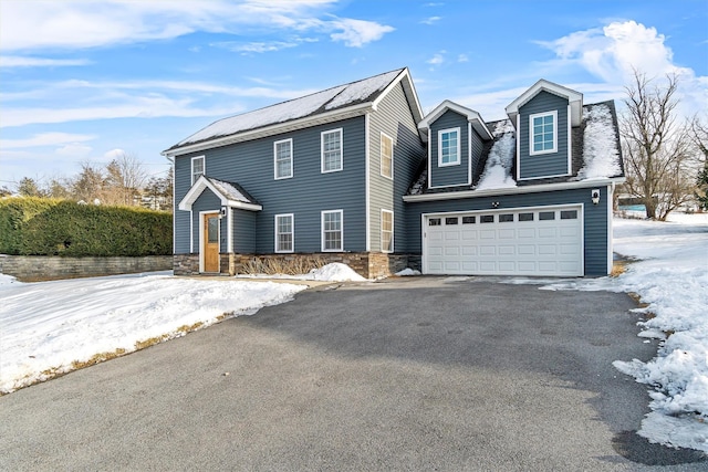 view of front of home featuring driveway, stone siding, and an attached garage