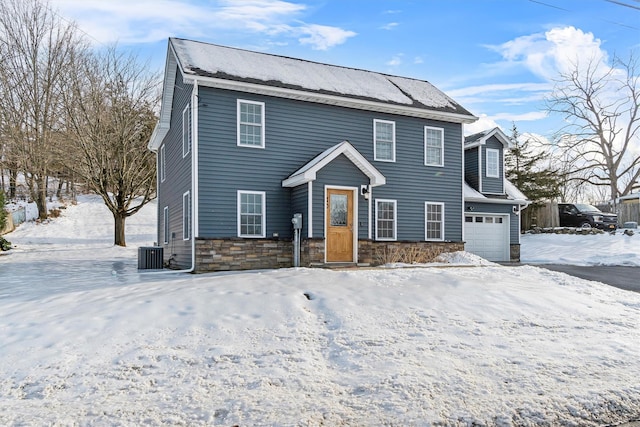 colonial home featuring stone siding, central AC unit, and an attached garage