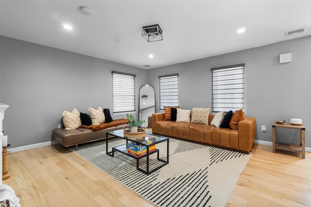 living room featuring light wood-style flooring, visible vents, baseboards, and recessed lighting