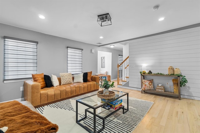 living room featuring light wood-style flooring, stairs, and recessed lighting