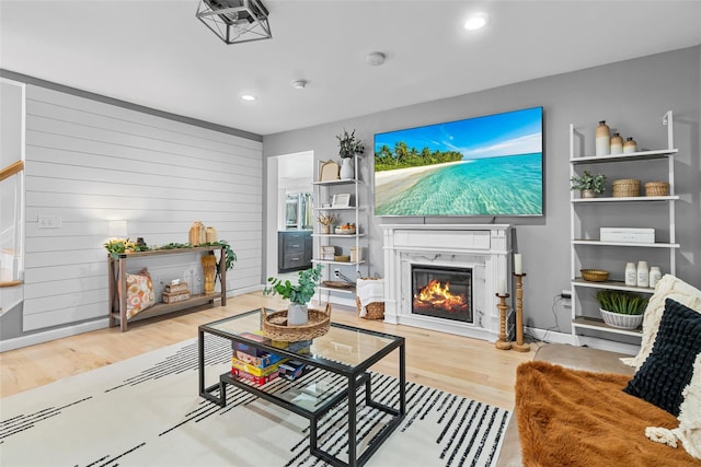 living area featuring light wood-type flooring, a glass covered fireplace, and recessed lighting