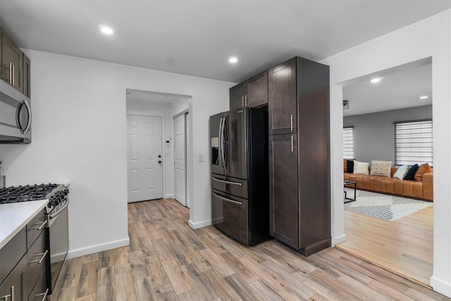 kitchen with stainless steel appliances, light countertops, light wood finished floors, and dark brown cabinets