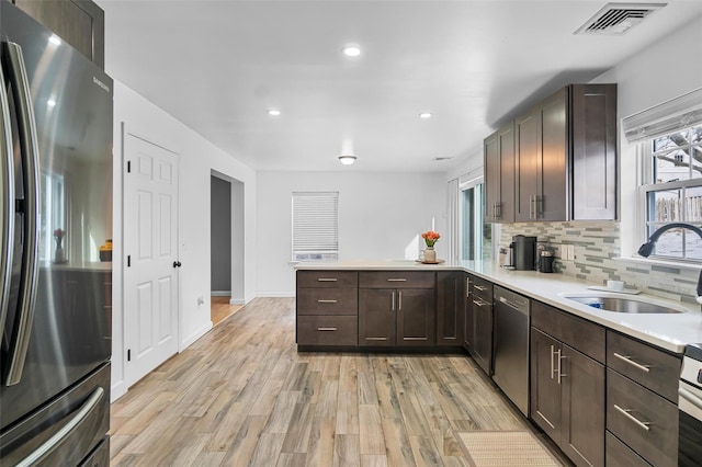 kitchen featuring light countertops, visible vents, decorative backsplash, appliances with stainless steel finishes, and a sink