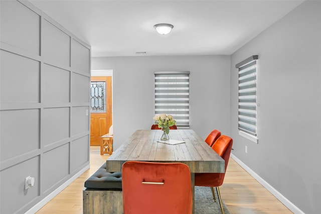 dining room featuring light wood finished floors, visible vents, and baseboards