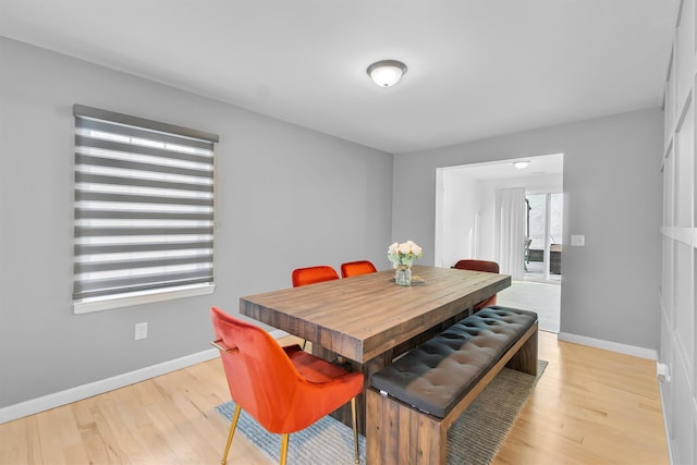 dining area with baseboards and light wood finished floors