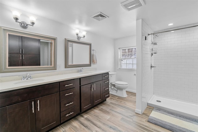 bathroom with toilet, wood finished floors, a sink, and visible vents