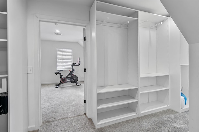 spacious closet featuring light carpet, vaulted ceiling, and visible vents