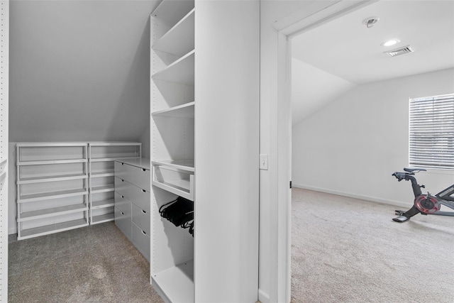 spacious closet with vaulted ceiling, visible vents, and dark carpet