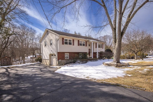 bi-level home with driveway, a garage, and brick siding