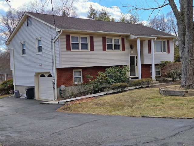 split foyer home featuring a garage, brick siding, driveway, and a front lawn